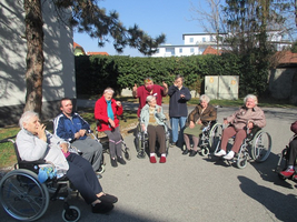 Ältere Menschen in Rollstühlen genießen einen sonnigen Tag im Freien.