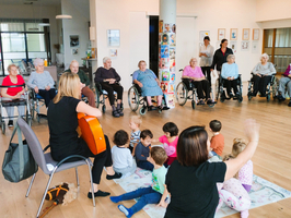 Musiktherapie mit Senioren und Kleinkindern in einem Gemeinschaftsraum.