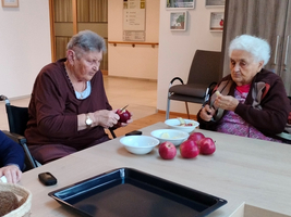 Zwei ältere Frauen schälen Äpfel an einem Tisch.