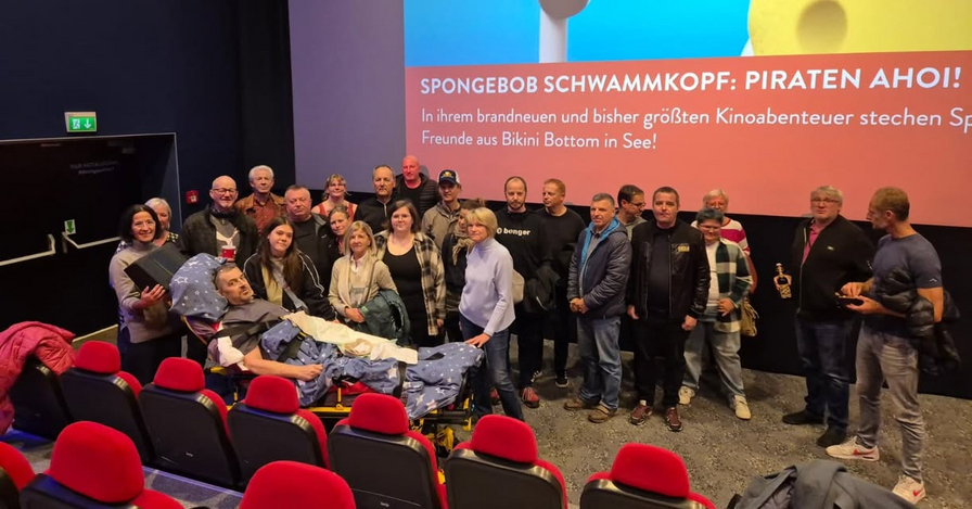 Gruppe von Menschen posiert lächelnd vor einer Leinwand im Kino.