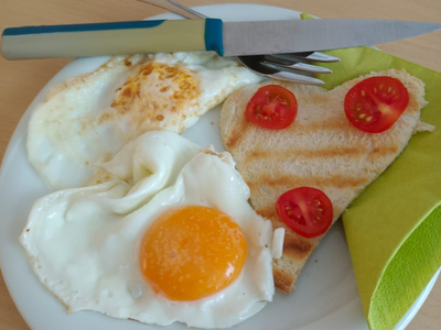 Ein Frühstücksgericht mit Spiegelei, Grilltoast, Tomaten und einer grünen Melonenhälfte.