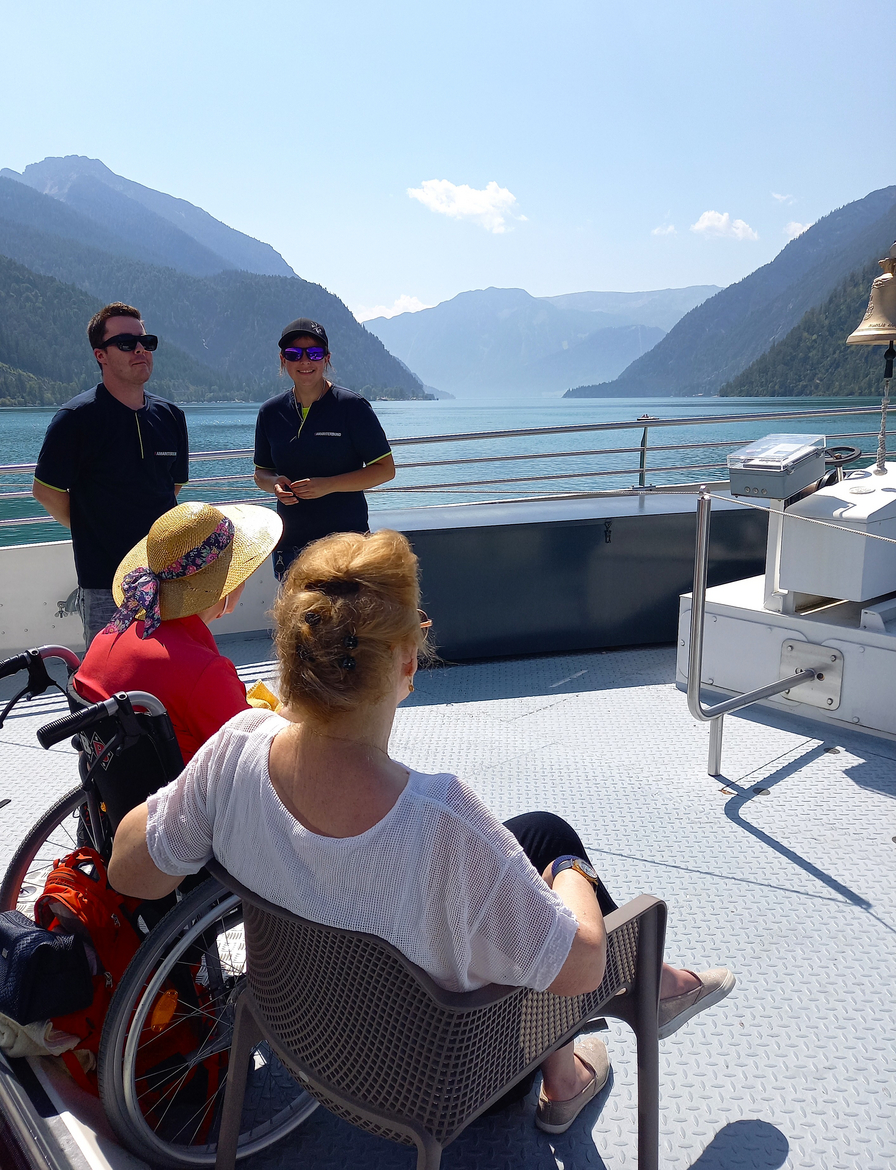Menschen auf einem Boot mit Blick auf eine malerische Berglandschaft.