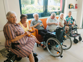 Sechs ältere Menschen in einer Einrichtung genießen Eis in einem hellen Raum.