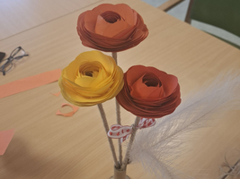 Ein Strauß aus bunten Papierblumen in einem Vasenständer.