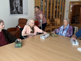 Ältere Frauen sitzen um einen Tisch in einem Gemeinschaftsraum.