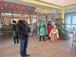 Eine Gruppe von Menschen in festlicher Kleidung steht vor einem Weihnachtsbaum.