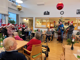 Weihnachtsfeier mit singenden Gästen und Musikern in festlicher Atmosphäre.