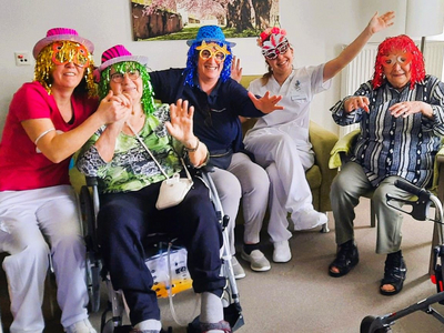 Fünf Personen in bunten Hüten feiern fröhlich zusammen in einem Raum.
