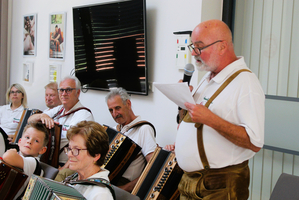 Musikgruppe spielt Akkordeon, während ein Mann spricht.