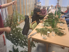 Gruppenaktivität: Menschen erstellen Weihnachtsdekoration mit Tannenzweigen und Flaschen.