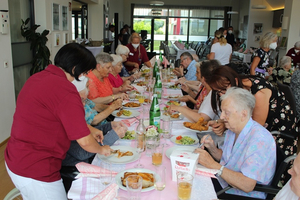 Eine Gruppe von Senioren genießt ein gemeinsames Mittagessen in einem Speisesaal.