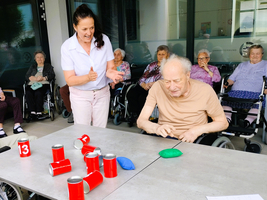 Eine Betreuerin spielt mit einem älteren Mann ein Geschicklichkeitsspiel.