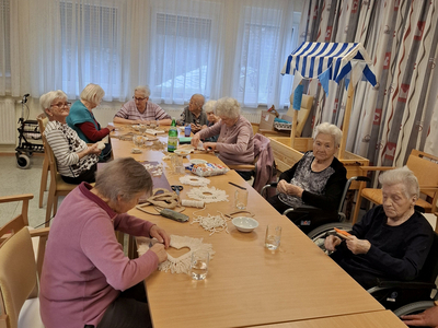 Ältere Frauen basteln gemeinsam an einem Tisch in einem Tagesheim.