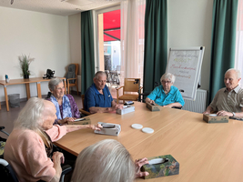Senioren sitzen an einem Tisch und diskutieren aktiv in einem Gruppentreffen.