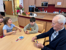 Drei Personen spielen Karten in einer gemütlichen Wohnumgebung.