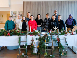 Gruppe von Personen präsentiert selbstgemachte Weihnachtsdekorationen auf einem Tisch.