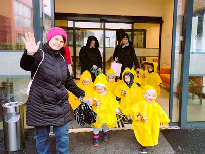 Eine Frau und Kinder in Regencapes gehen nach draußen.