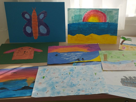 Bunte Zeichnungen von Tieren, Landschaften und einem Schiff auf einem Tisch.