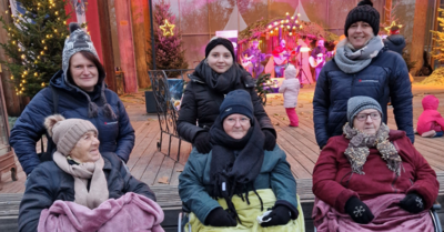 Fünf Personen in winterlicher Kleidung, umgeben von festlicher Dekoration und Musik.
