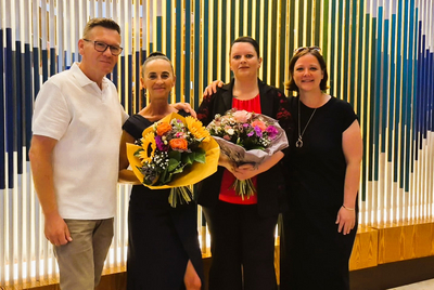Vier Personen stehen gemeinsam mit Blumensträußen in den Händen.
