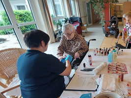 Ältere Frauen nehmen an einer Nagelpflege-Aktivität in einem Gemeinschaftsraum teil.