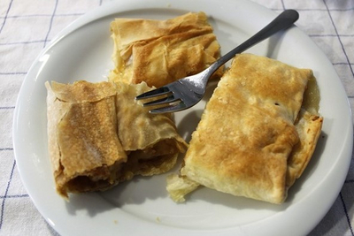 Drei Stücke warmen, gefüllten Strudels auf einem Teller mit einer Gabel.