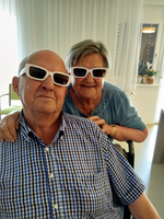 Ein älteres Paar trägt Sonnenbrillen und lächelt in die Kamera.