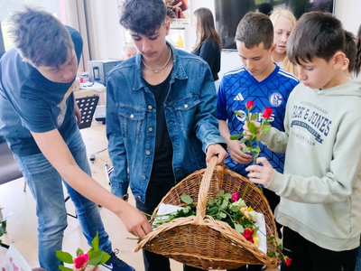 Jugendliche halten einen Korb mit Blumen und verteilen sie.