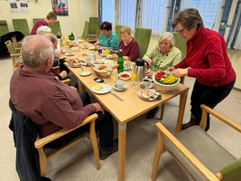 Ältere Menschen sitzen an einem Tisch, genießen ein gemeinsames Essen.
