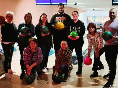 Eine Gruppe von zehn Personen beim Bowling, jeder hält eine Bowlingkugel.