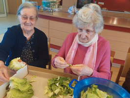 Zwei Frauen sortieren Salatblätter in einer Küche.