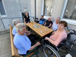 Ältere Menschen sitzen an einem Tisch im Freien und verbringen Zeit miteinander.