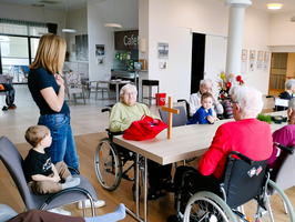 Eine Gruppenveranstaltung mit Senioren im Pflegeheim, begleitet von Kindern.