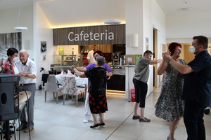 Tanzende Menschen in einer Cafeteria, fröhliche Atmosphäre und Gemeinschaft.