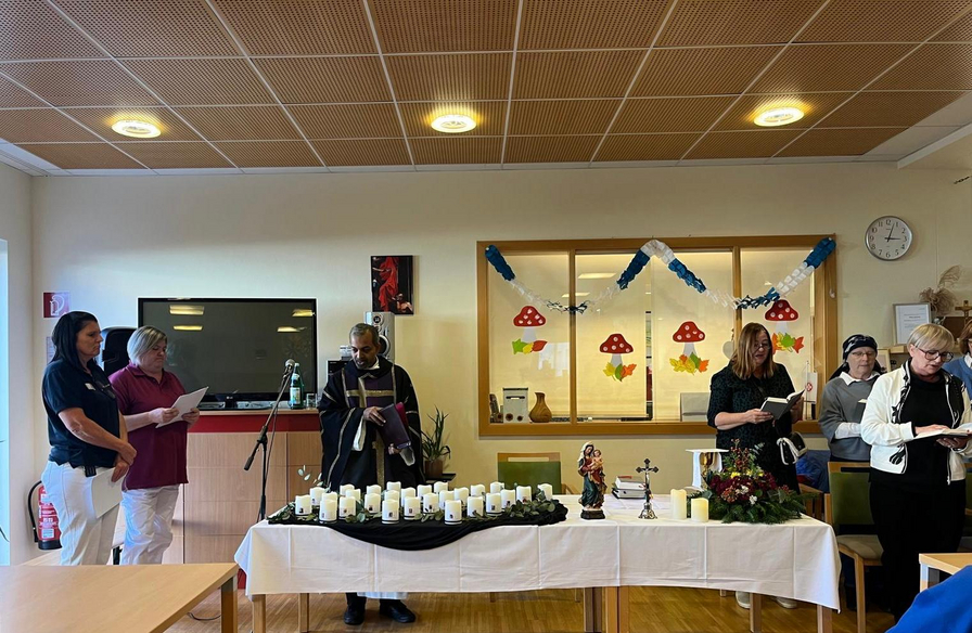 Eine Gruppe von Personen steht um einen Tisch mit Kerzen und einem Weihnachtsornament.