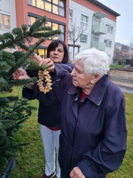 Zwei Frauen dekorieren einen Weihnachtsbaum im Freien.