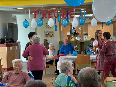 Feierliche Versammlung mit bunten Ballons und fröhlichen Gesprächen.