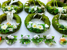 Blumengestecke und dekorative Kränze mit frischen Pflanzen und Ostermotiven.