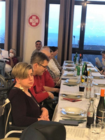 Eine Gruppe von Menschen sitzt an einem festlich gedeckten Tisch in einem Raum.