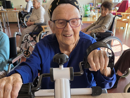 Ältere Frau trainiert mit einem kleinen Handtrainer in einer Pflegeeinrichtung.