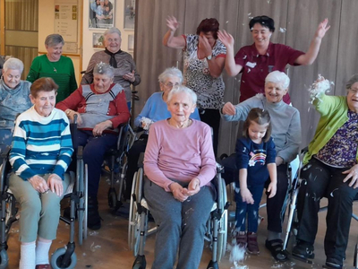 Ältere Menschen und ein Kind erleben einen fröhlichen Moment mit Konfetti.