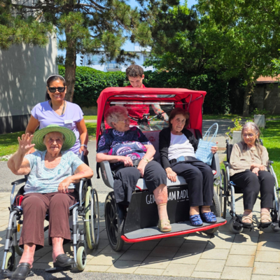 Ältere Menschen in Rollstühlen genießen einen sonnigen Tag im Freien.
