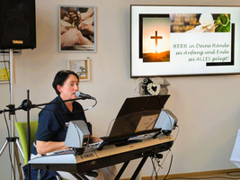 Frau singt und spielt Keyboard bei einer religiösen Veranstaltung.