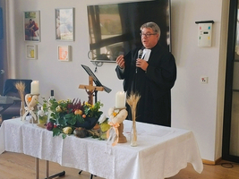 Ein Pastor spricht vor einem festlich gedeckten Tisch mit Dekoration.