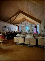 Ein Raum voll von Krankenbetten und Publikum bei einer Veranstaltung.