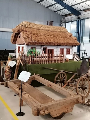 Ein traditionelles Haus mit Strohdach und weißer Fassade in einem Museum.