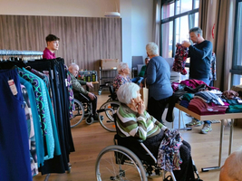 Senioren in Rollstühlen wählen Kleidung in einem hellen Raum.