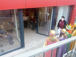 Besuch von Kindern in Kostümen bei älteren Menschen in einem Wohnheim.