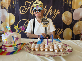 Ein älterer Mann feiert seinen Geburtstag mit einer Torte und festlicher Kopfbedeckung.