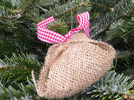 Jutesäckchen mit rot-weißem Band hängt in einem Weihnachtsbaum.